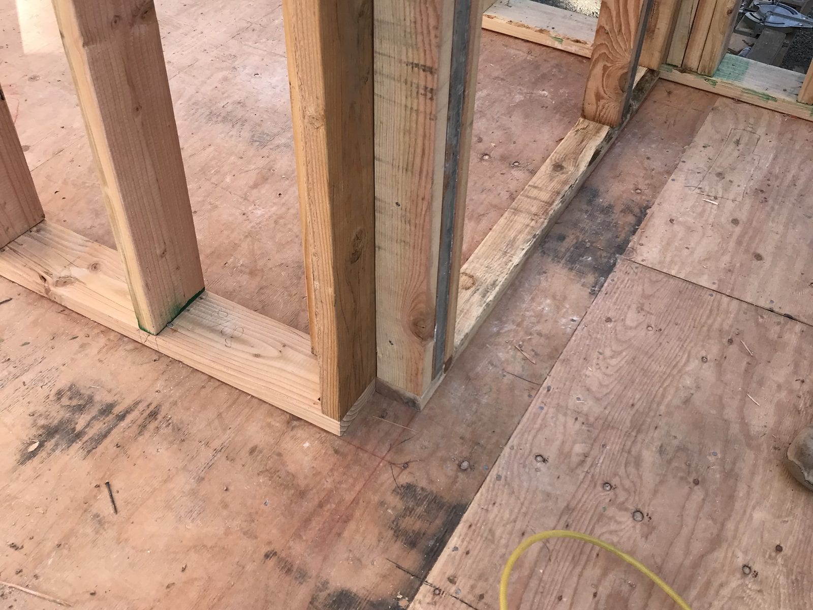 New interior stud partitions standing on a plywood subfloor inside an addition under construction