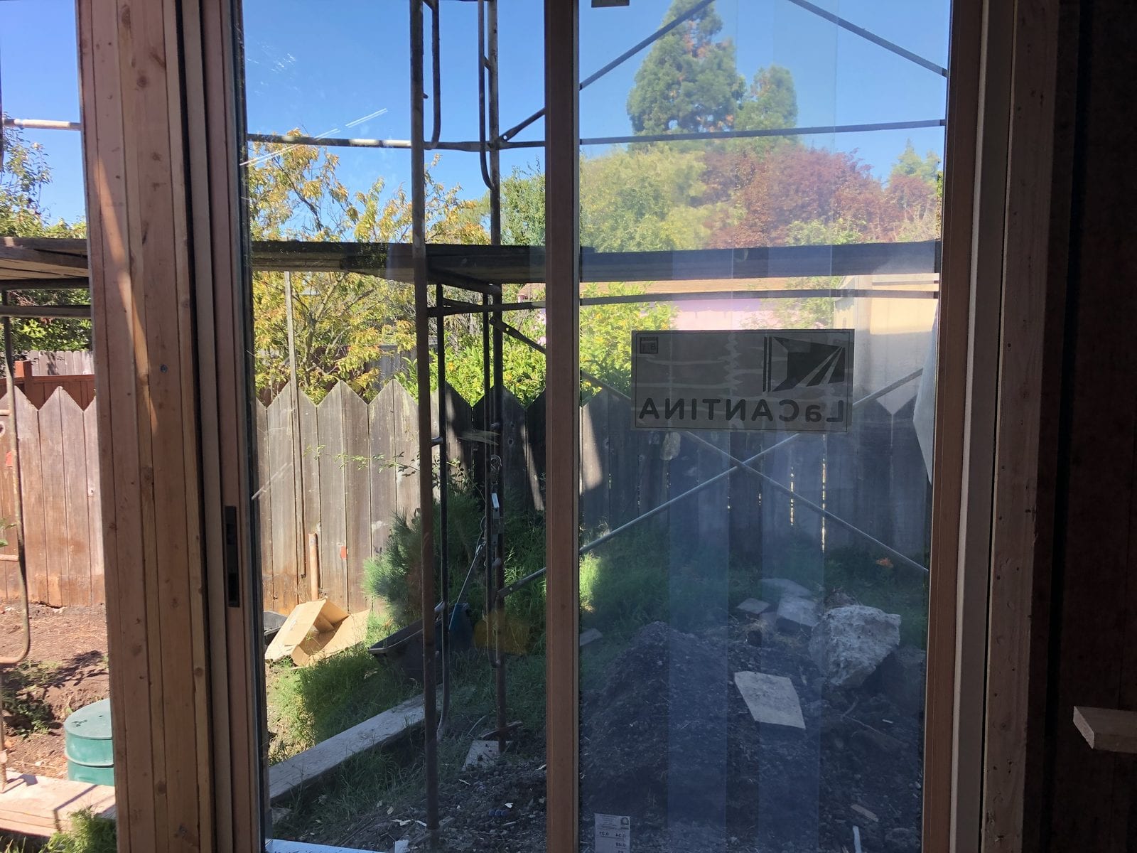 Multi-panel folding glass door unit installed in a rear wall opening, looking out to a fenced garden