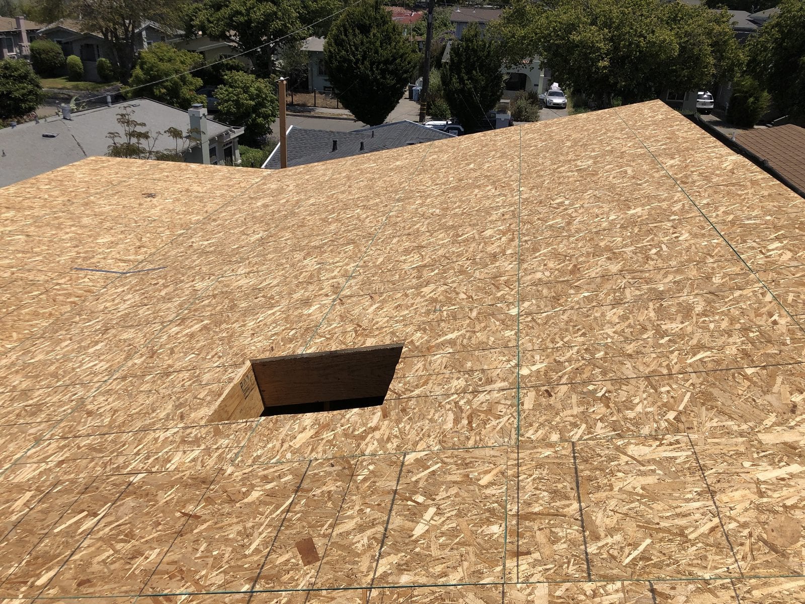 Hipped roof fully sheathed in OSB panels with a framed opening for a skylight, seen from above