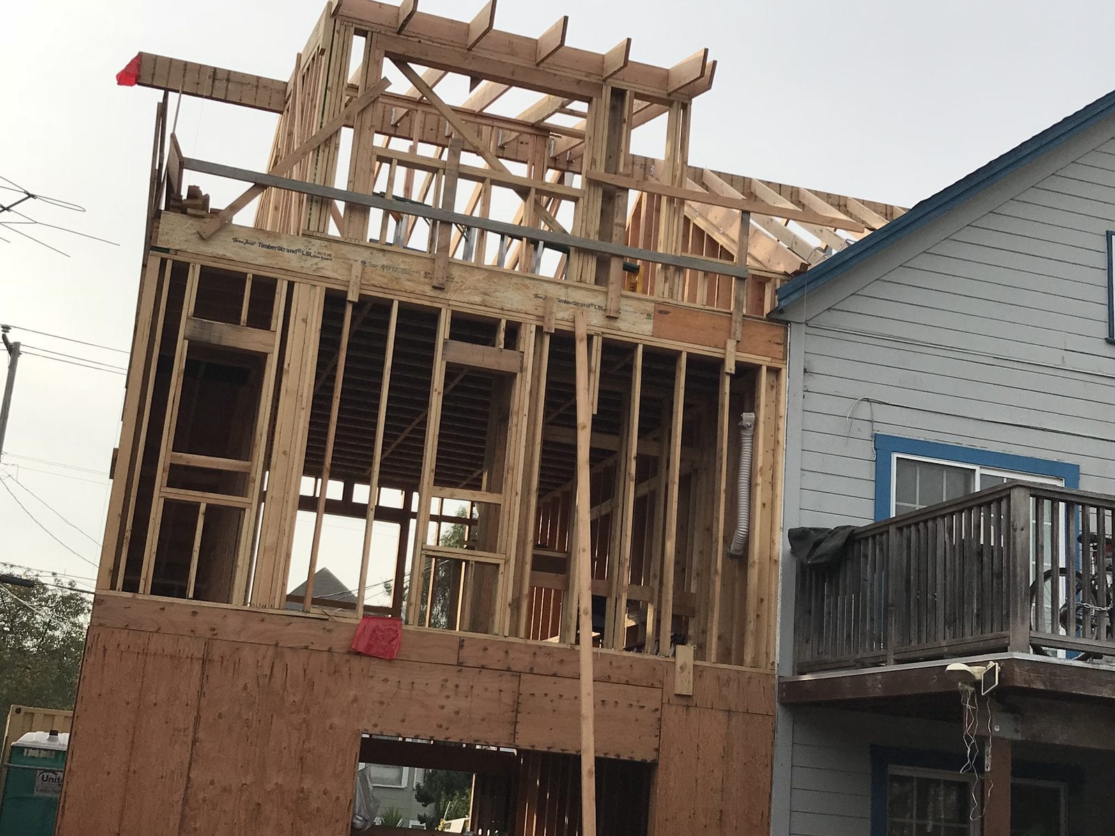Roof structure being framed on a second-storey addition, with rafters, a ridge beam and a steel strap tie above the new floor